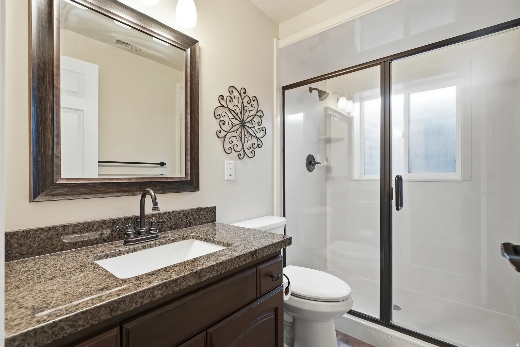 Bathroom featuring a dark wood-finish vanity with a granite countertop, undermount sink, and bronze-finish faucet