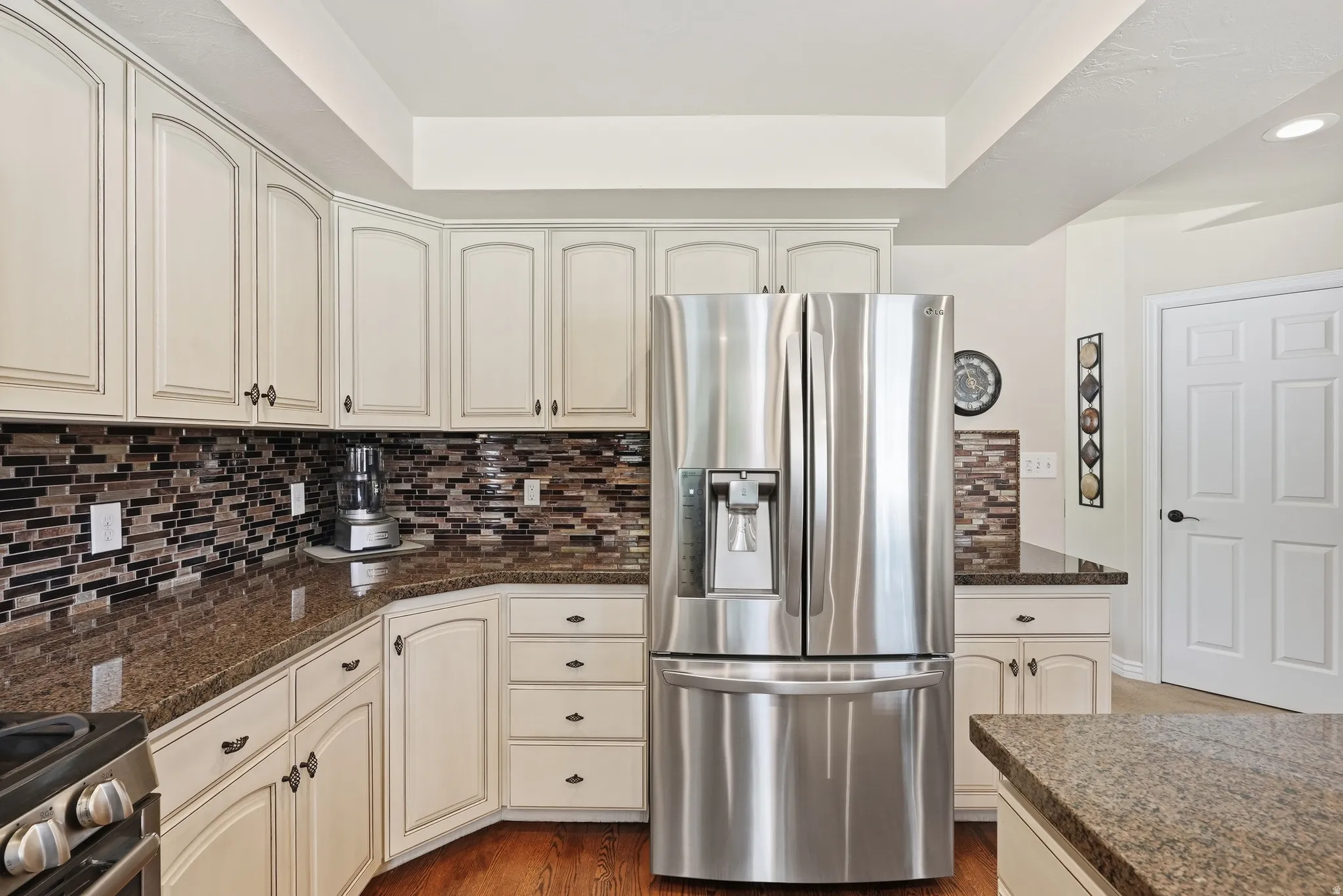Kitchen featuring custom-style cabinetry, dark speckled countertops, and a full tile backsplash