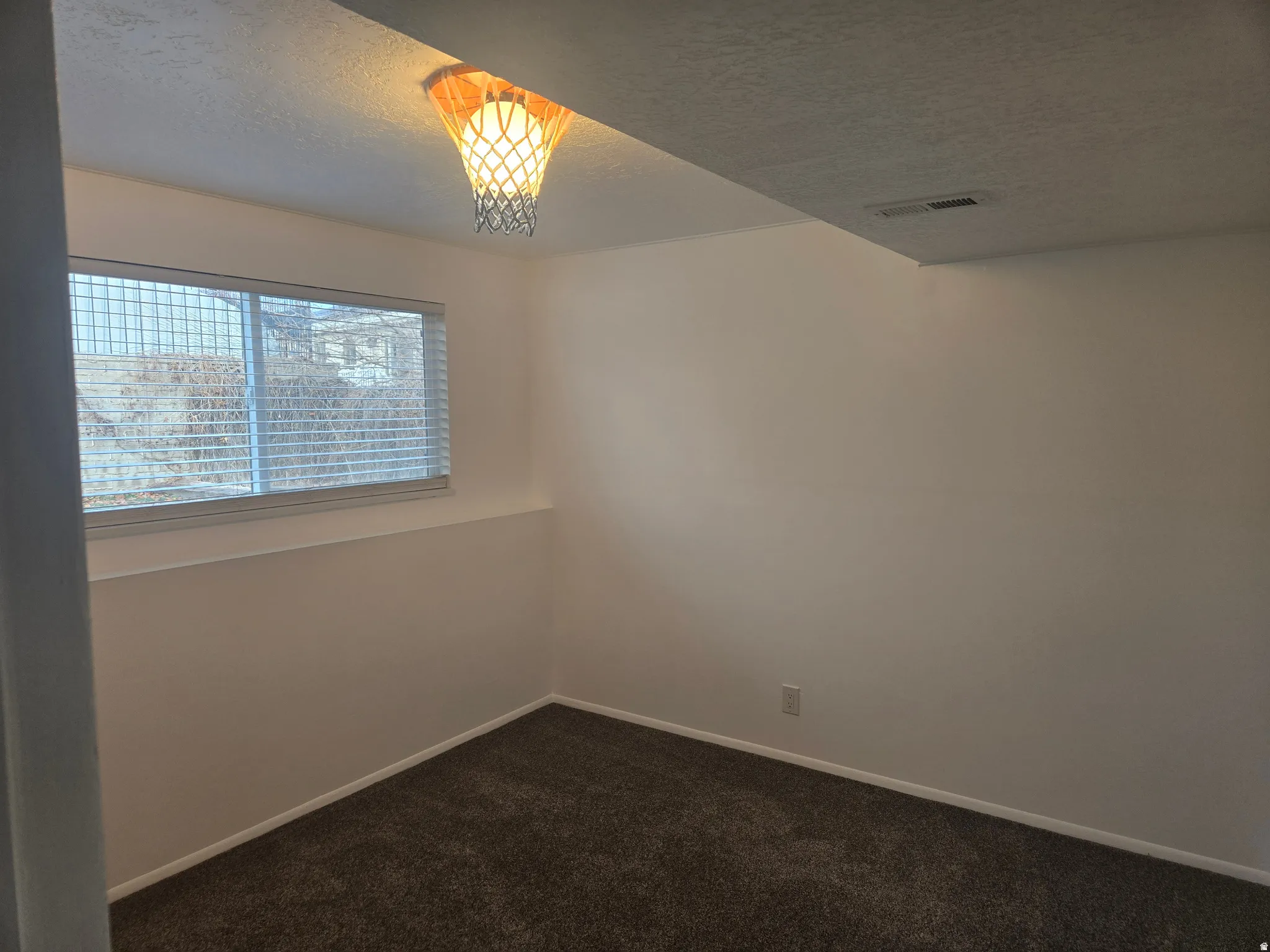 Room featuring soft gray carpeting, white walls, and a window with horizontal blinds