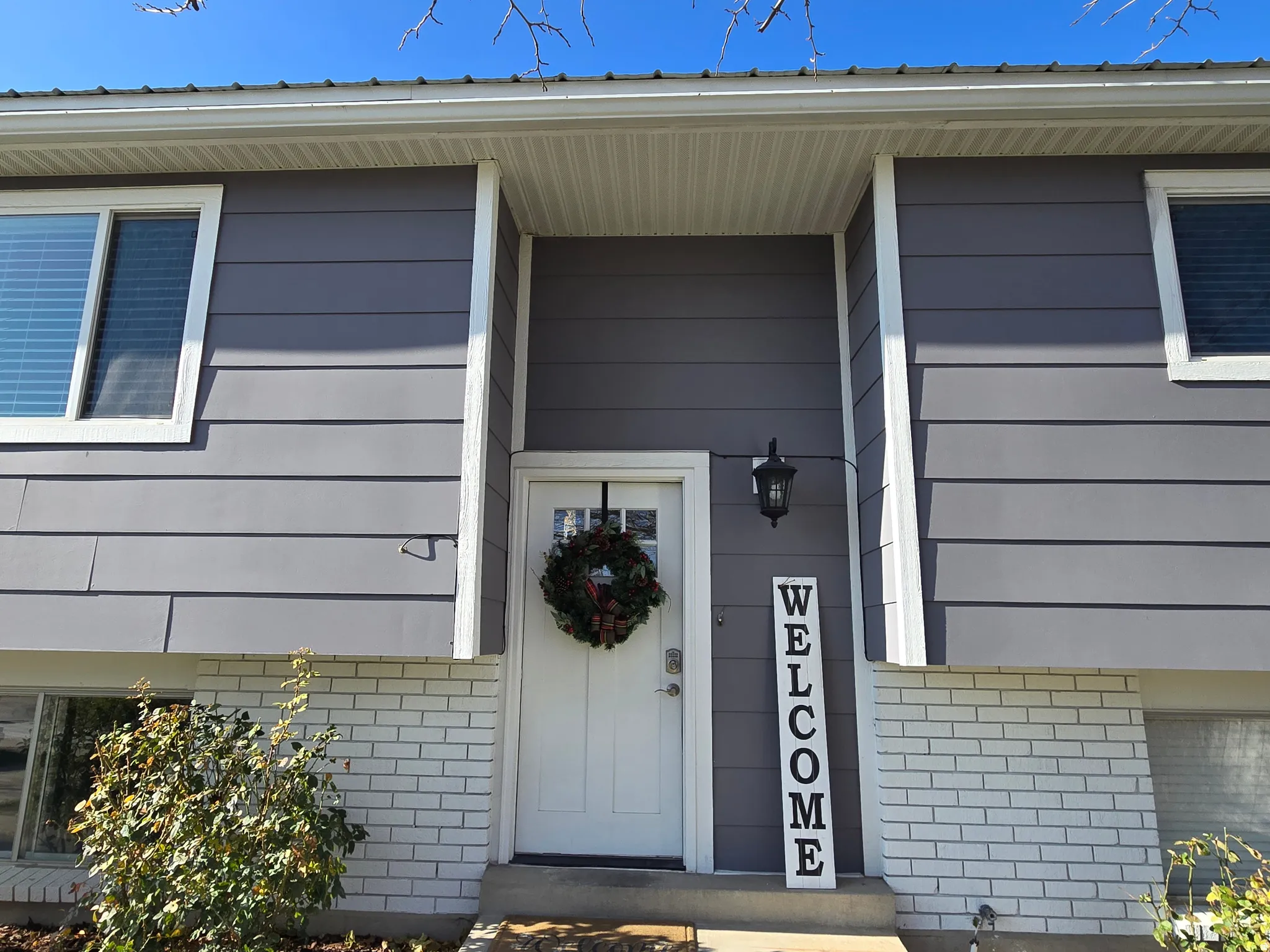 Gray horizontal siding facade with white trim and a white entry door