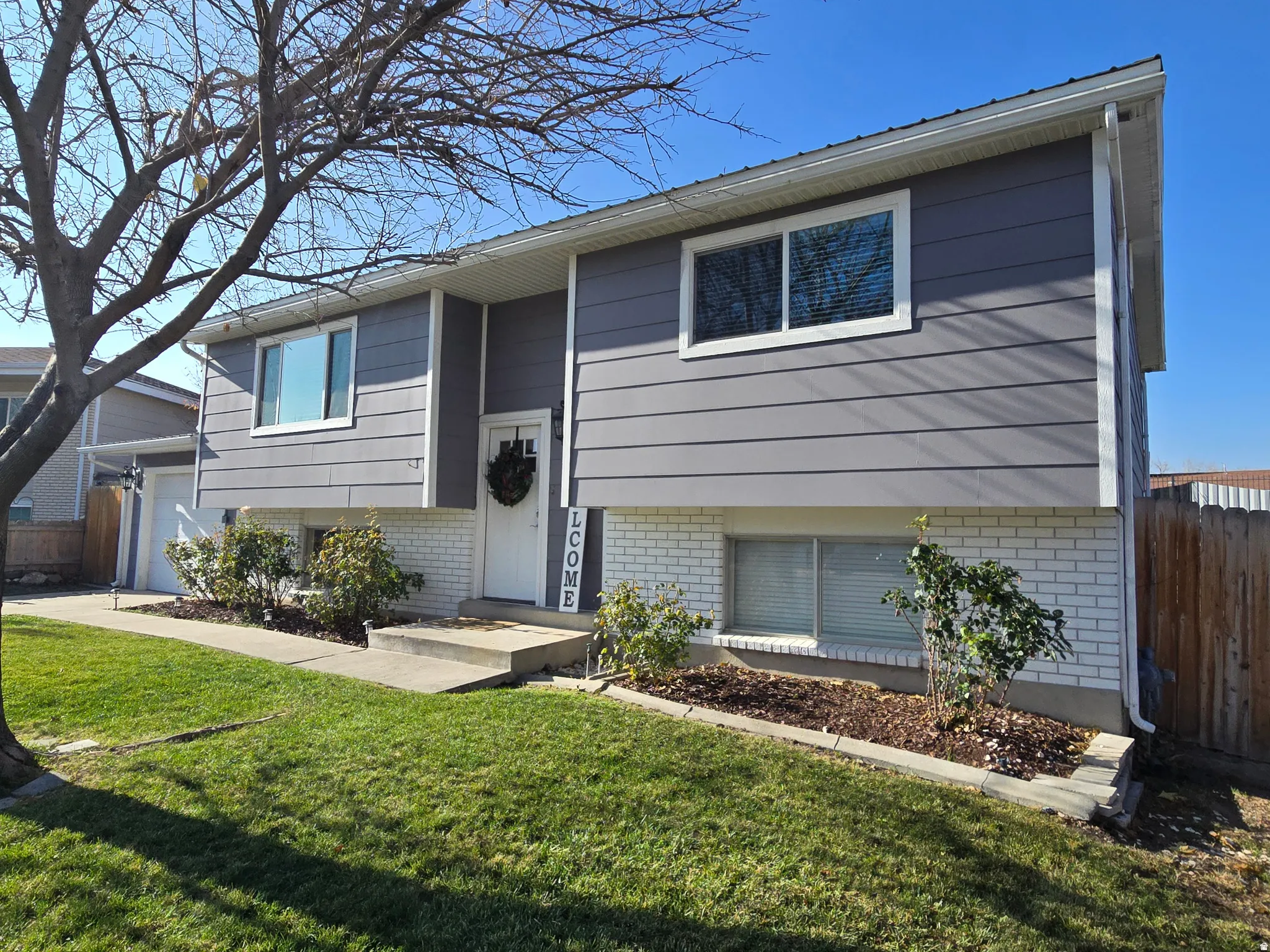 Split-level residence featuring gray horizontal siding and white brick accents