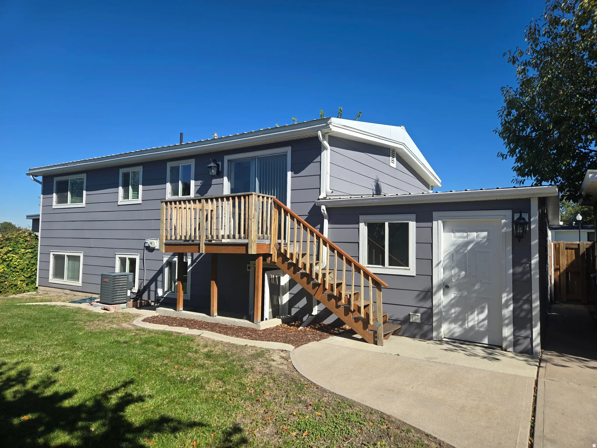 Rear exterior featuring a wooden deck with stairs, gray horizontal siding, and multiple windows