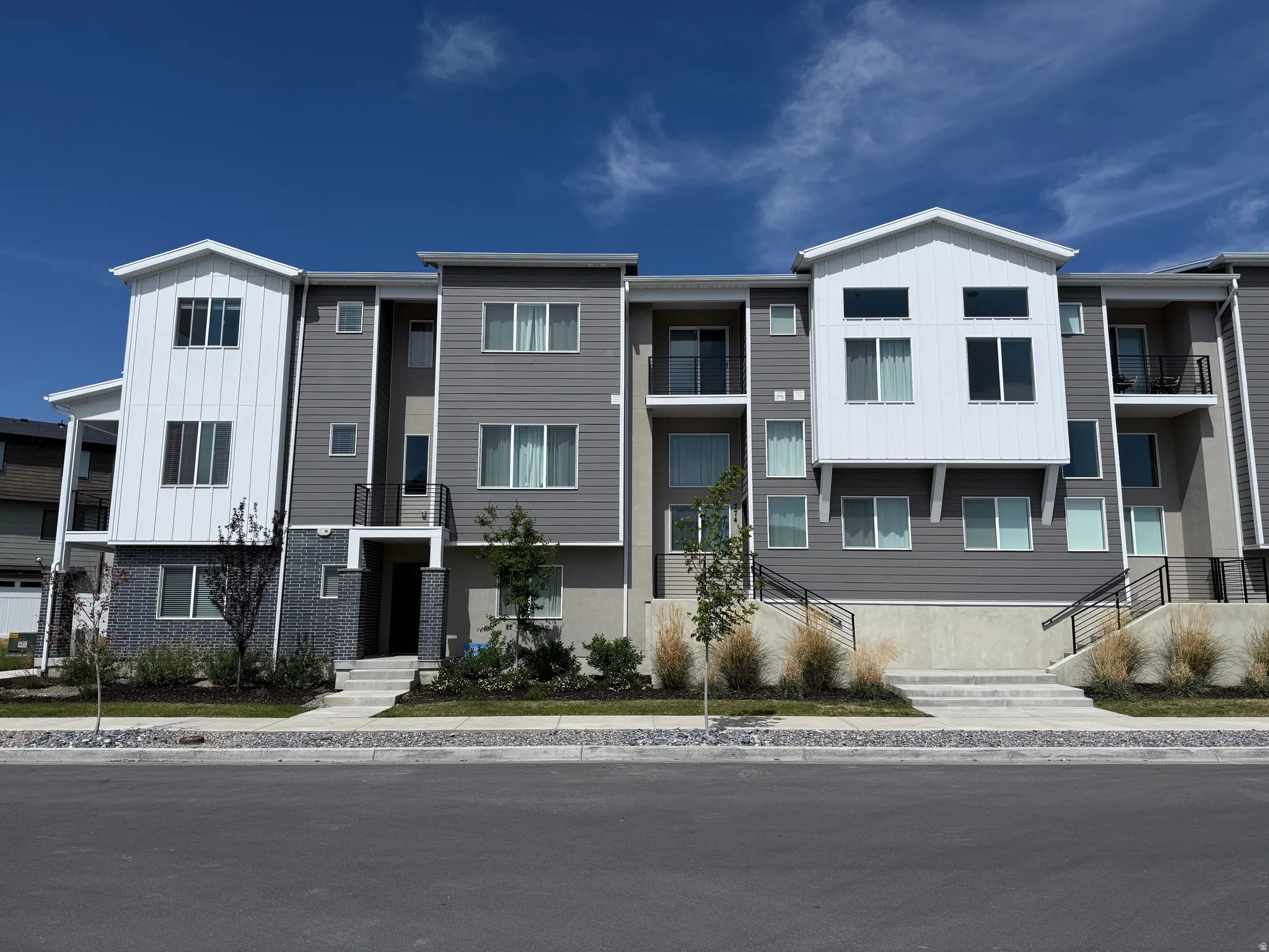 Contemporary multi-story townhome residences featuring varied grey siding and white architectural accents