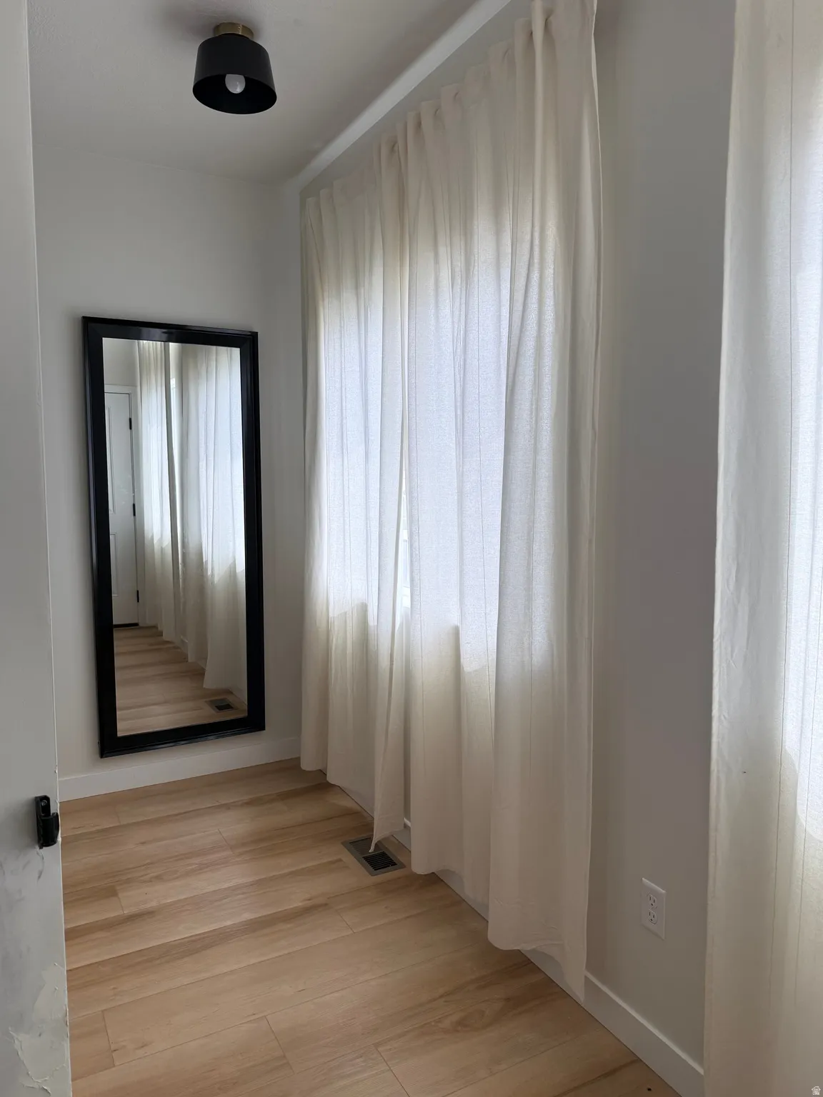 Hallway featuring wood-finish flooring and a full-length mirror