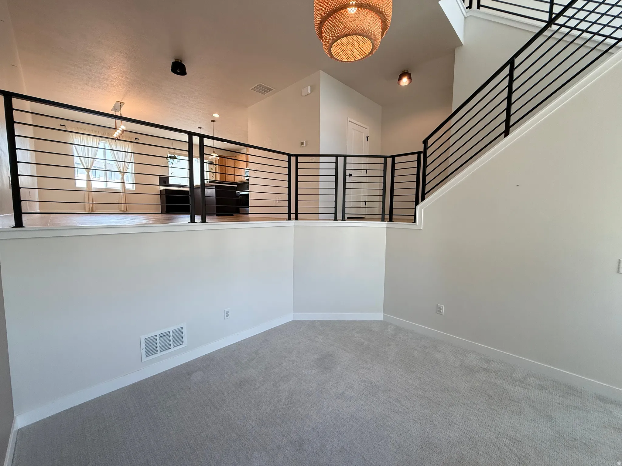 Multi-level interior featuring a modern black metal railing, light gray wall paint, and gray carpet