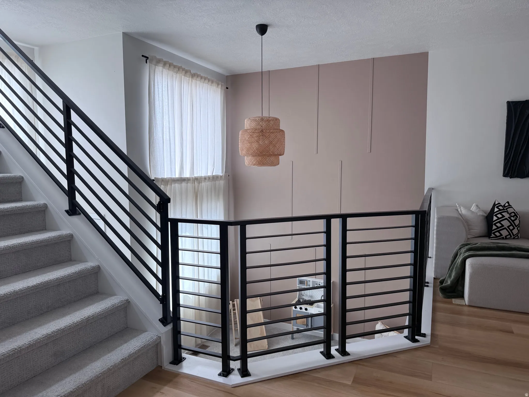 Upper-level landing featuring wood-finish flooring and contemporary black metal horizontal bar railing