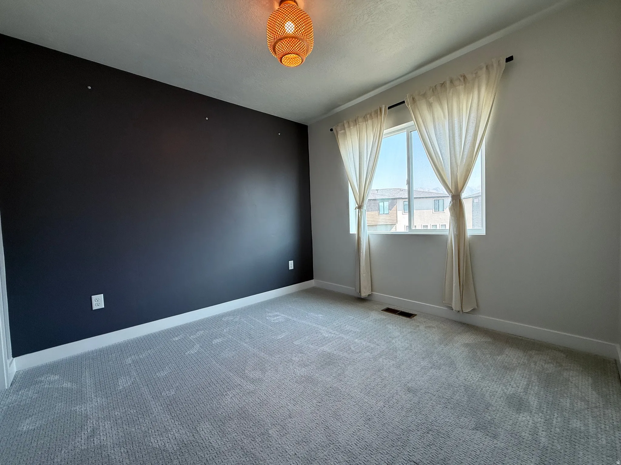 Recessed window with white trim, light gray carpet, dark accent wall, and a woven ceiling light fixture