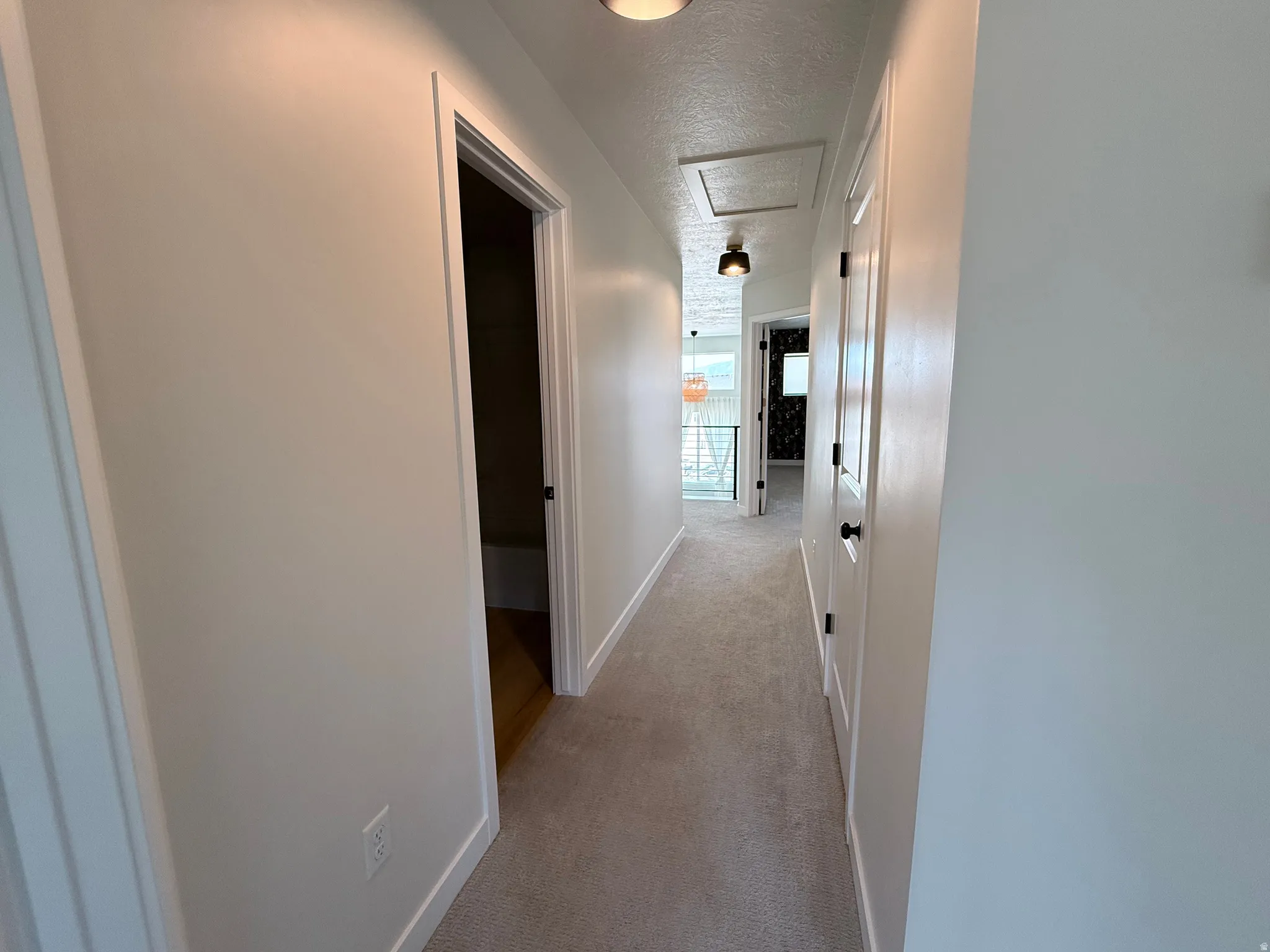 Carpeted hallway with white walls, recessed lighting, and a white access panel