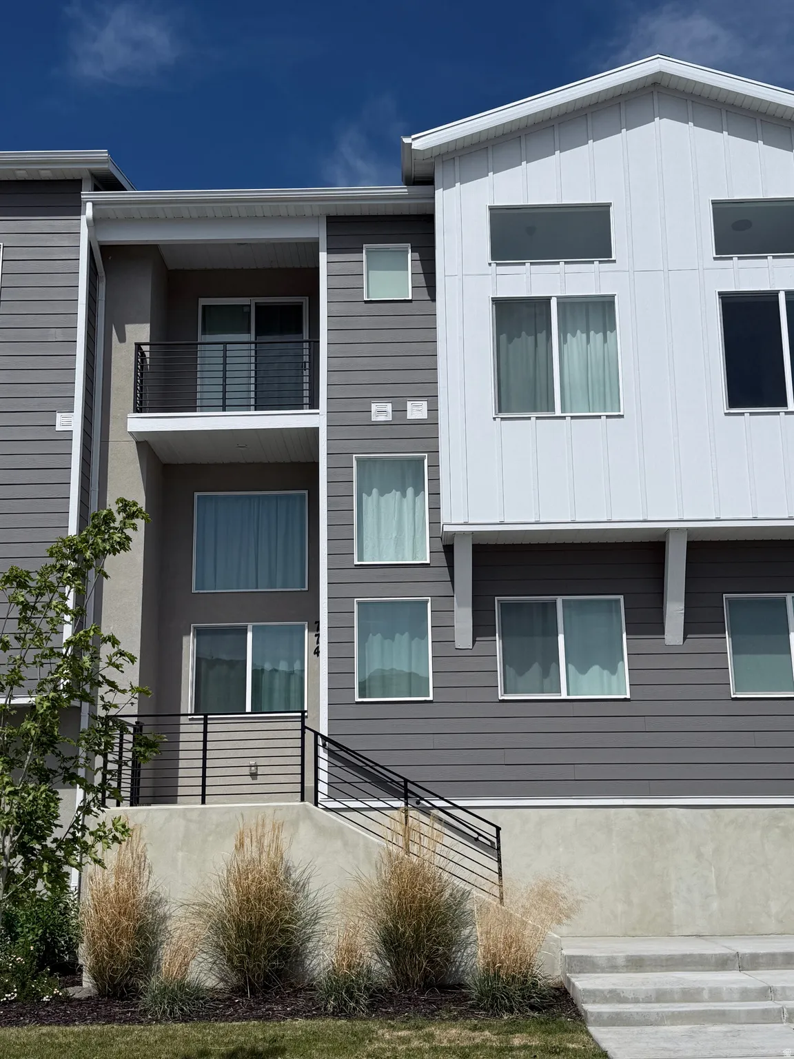 Contemporary multi-level exterior with a striking gray and white facade, accented by black railings