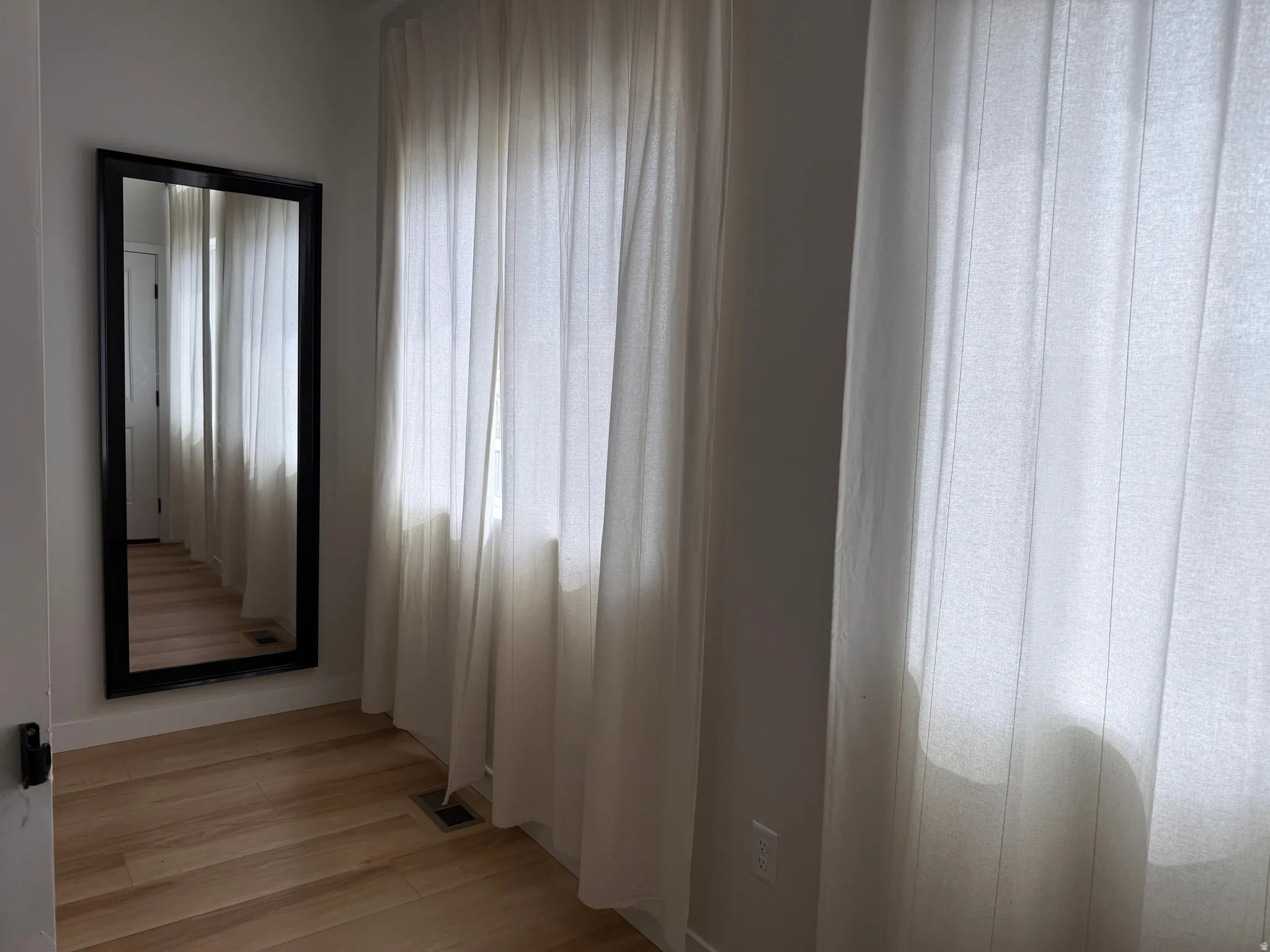 Wood-finish flooring with floor-to-ceiling sheer window treatments