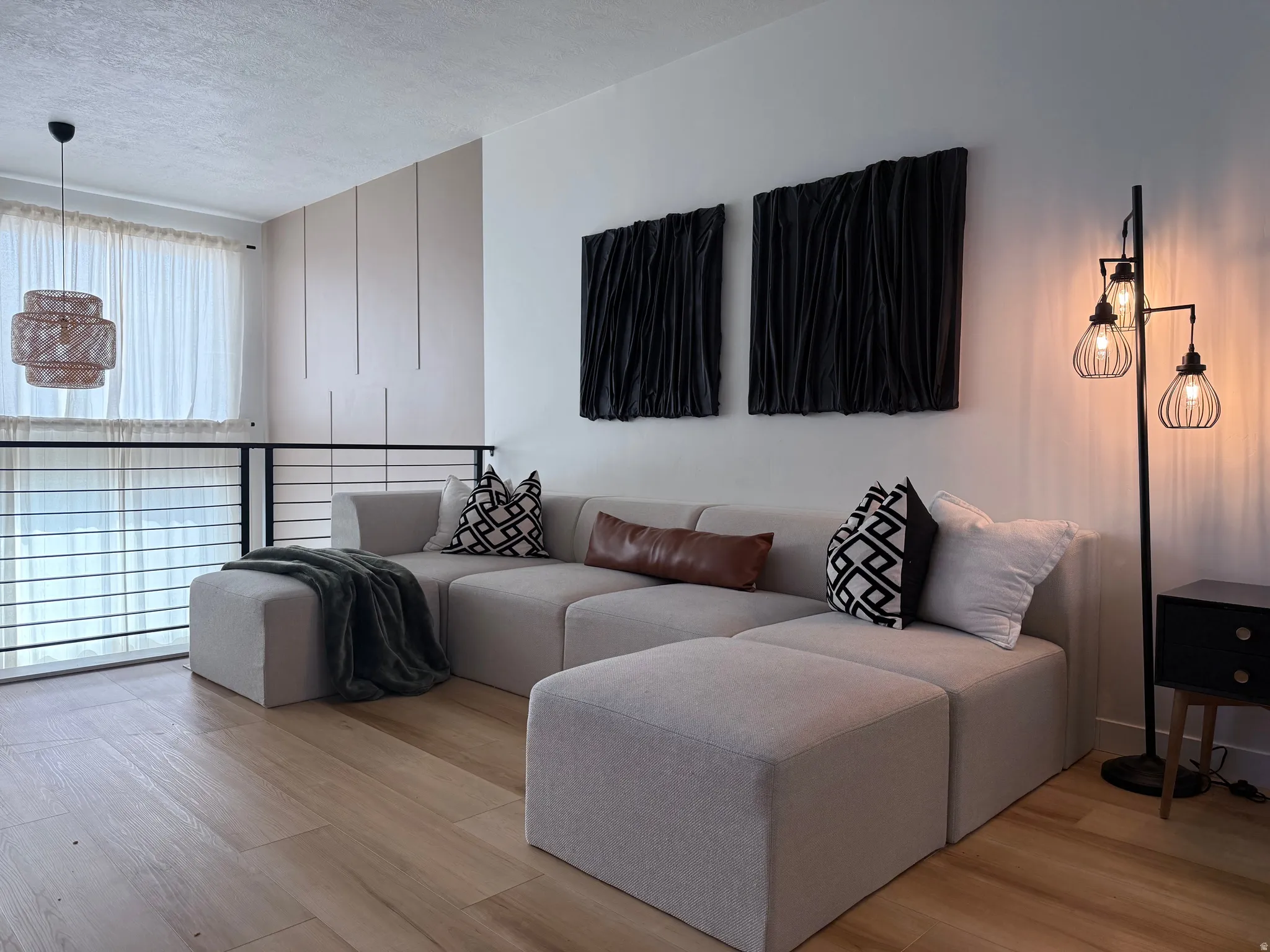 Loft space featuring wood-finish flooring, a contemporary black metal railing, and a decorative wall panel accent
