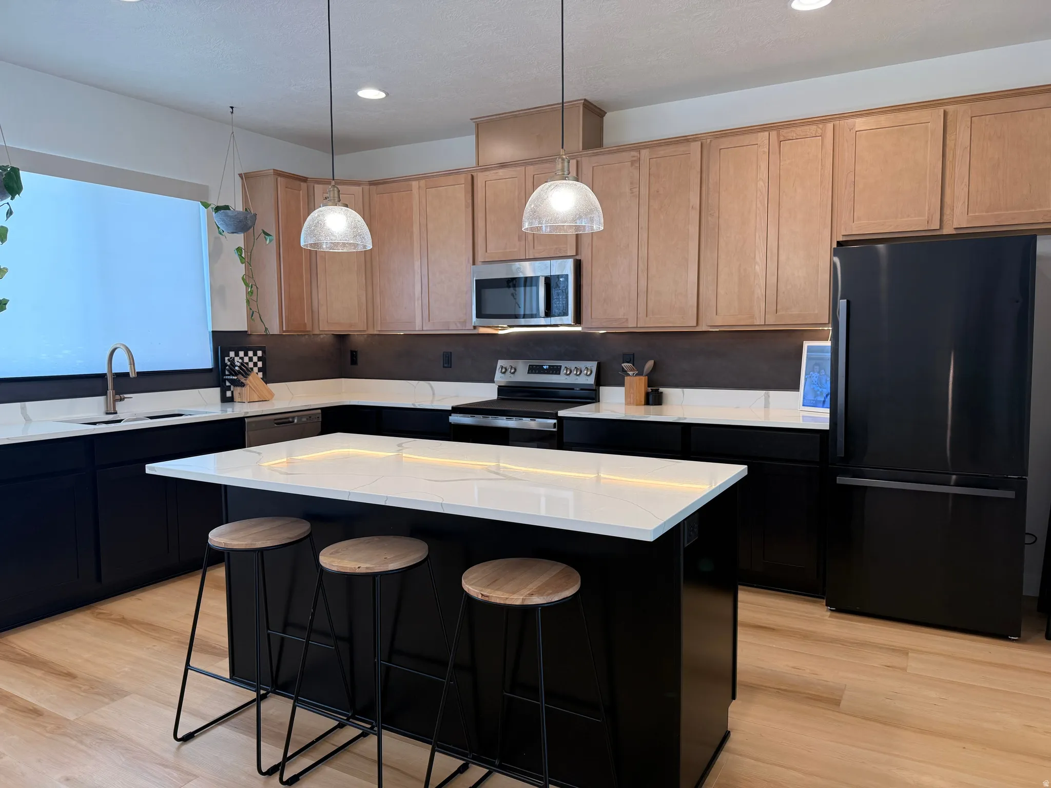Contemporary kitchen featuring a large central island with seating, white countertops, and wood-finish flooring