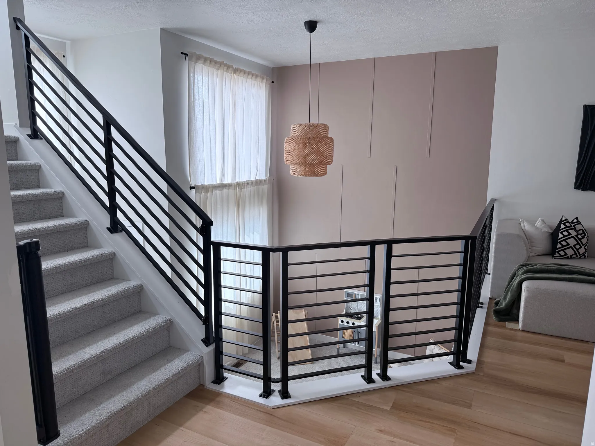 Modern black horizontal bar railings frame the staircase and upper landing