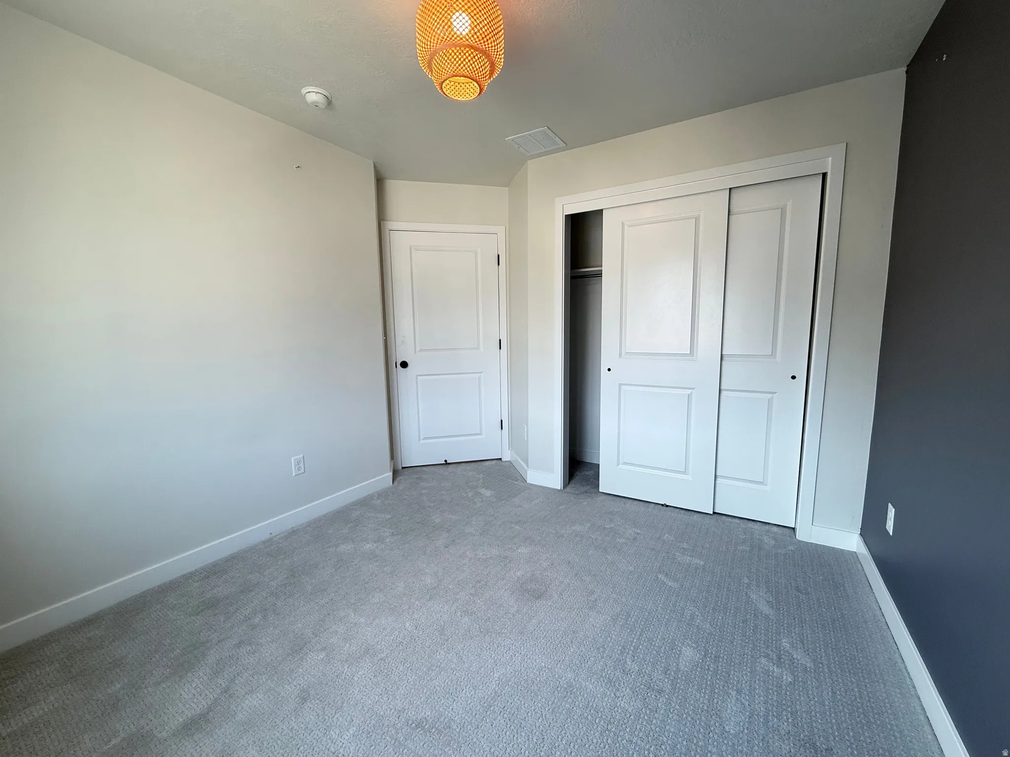 Carpeted flooring, white painted walls, a built-in closet with sliding doors, a recessed light fixture, and a single hinged door