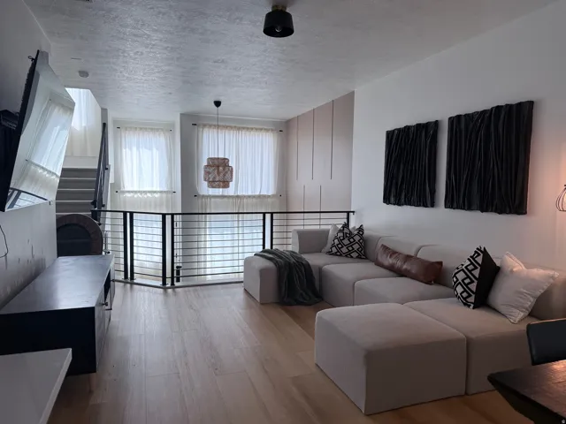 Open-concept living space featuring wood-finish flooring, a contemporary black metal railing, and high ceilings