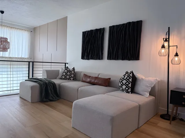 Open-concept living space featuring wood-finish flooring, a high ceiling, and a contemporary metal railing