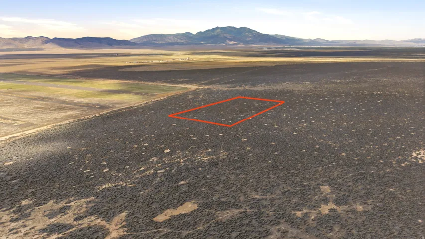 Expansive undeveloped land featuring natural desert vegetation, a level topography, and a distant mountain range backdrop. (LOCATION/BOUNDARIES HIGHLIGHTED)
