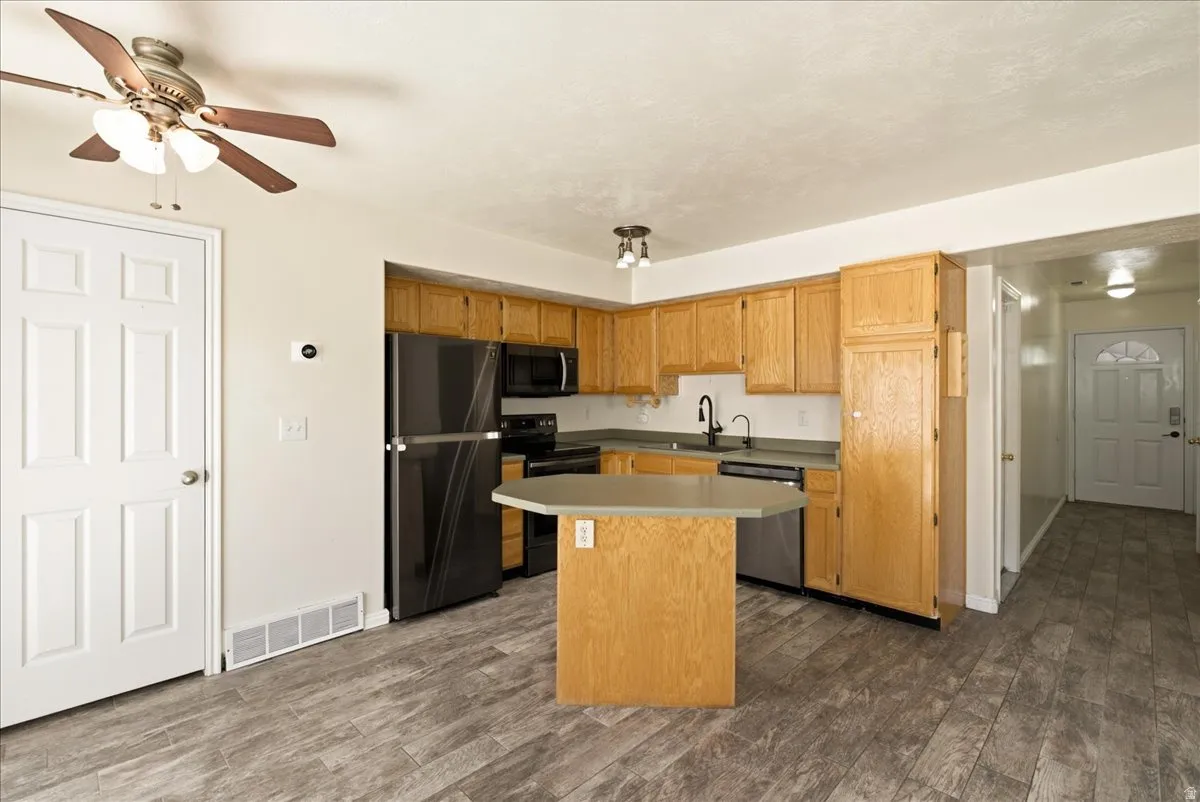 Kitchen featuring wood-finish cabinetry, black appliances, and peninsula with countertop seating