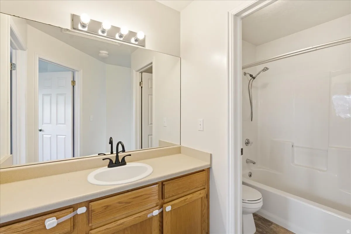 Bathroom featuring a light wood-finish vanity with a beige countertop, an oval undermount sink, and a matte black faucet