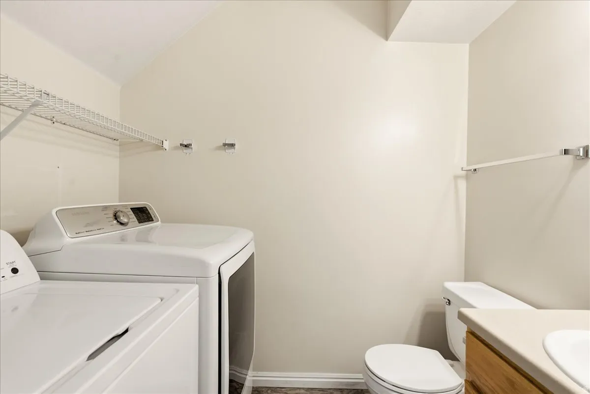 Dedicated laundry area featuring wire shelving, built-in wall hooks, and wood-finish flooring