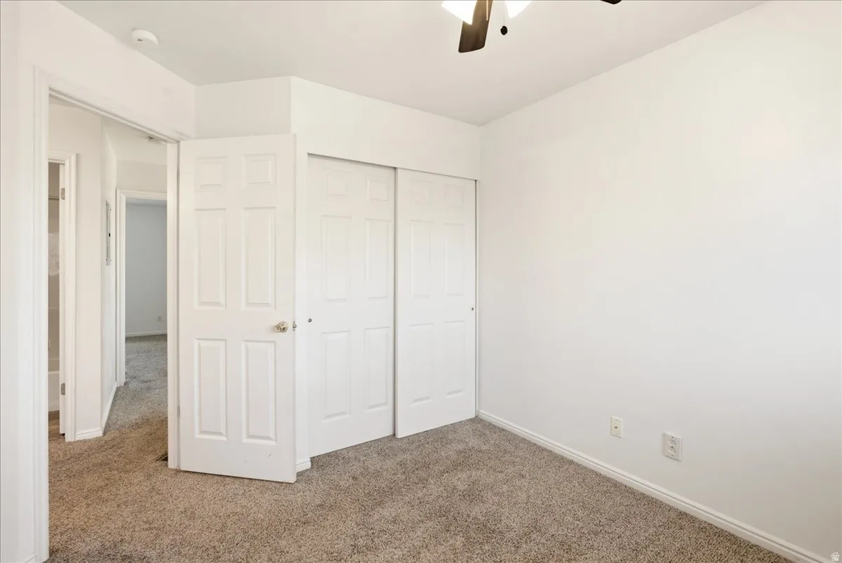 Carpeted room with white walls, a multi-panel door, and a sliding two-panel closet door