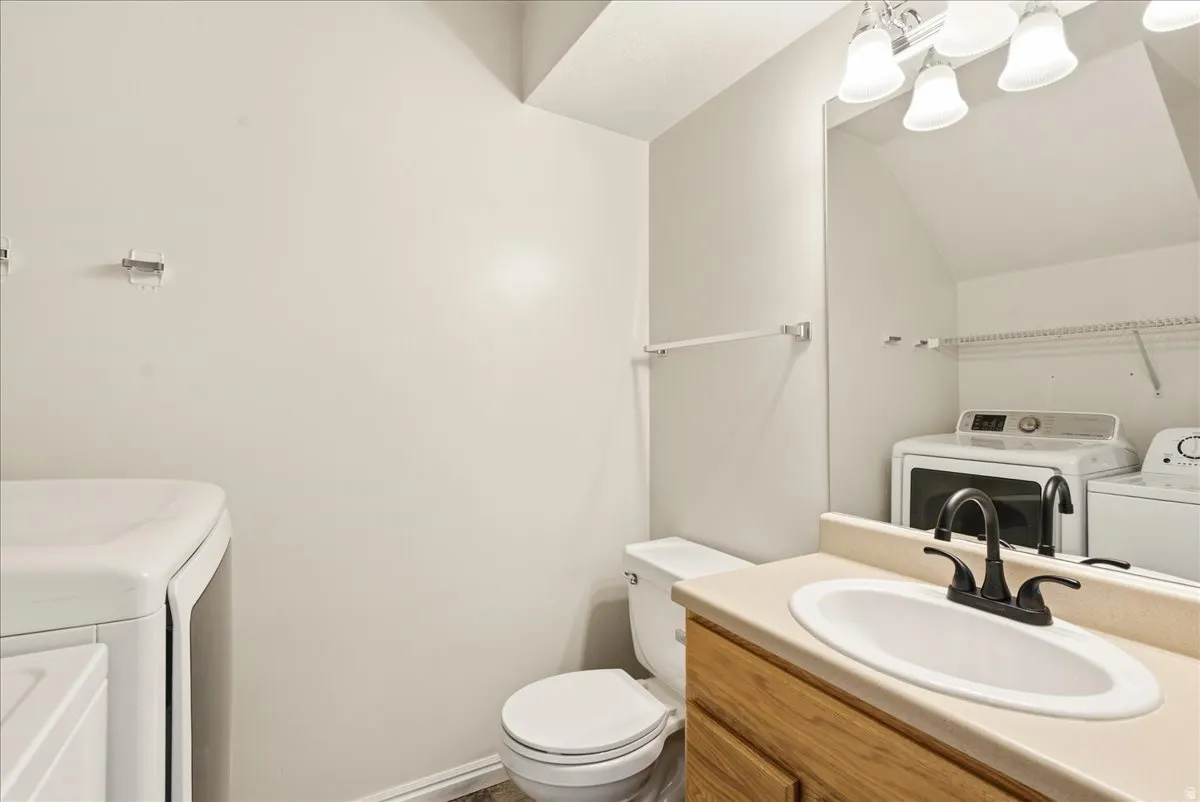 Bathroom vanity with a white oval sink, dark bronze faucet, and light wood-finish cabinetry