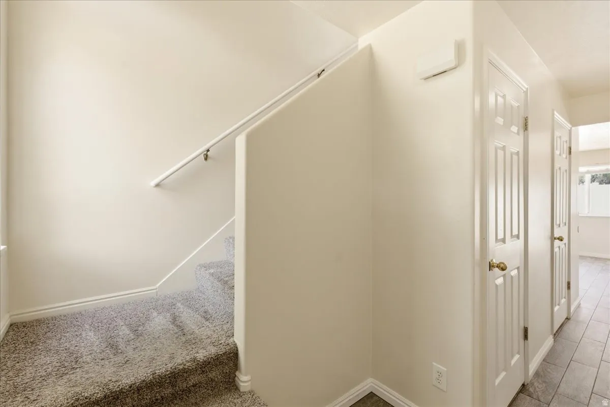 Carpeted staircase with white handrail and baseboards