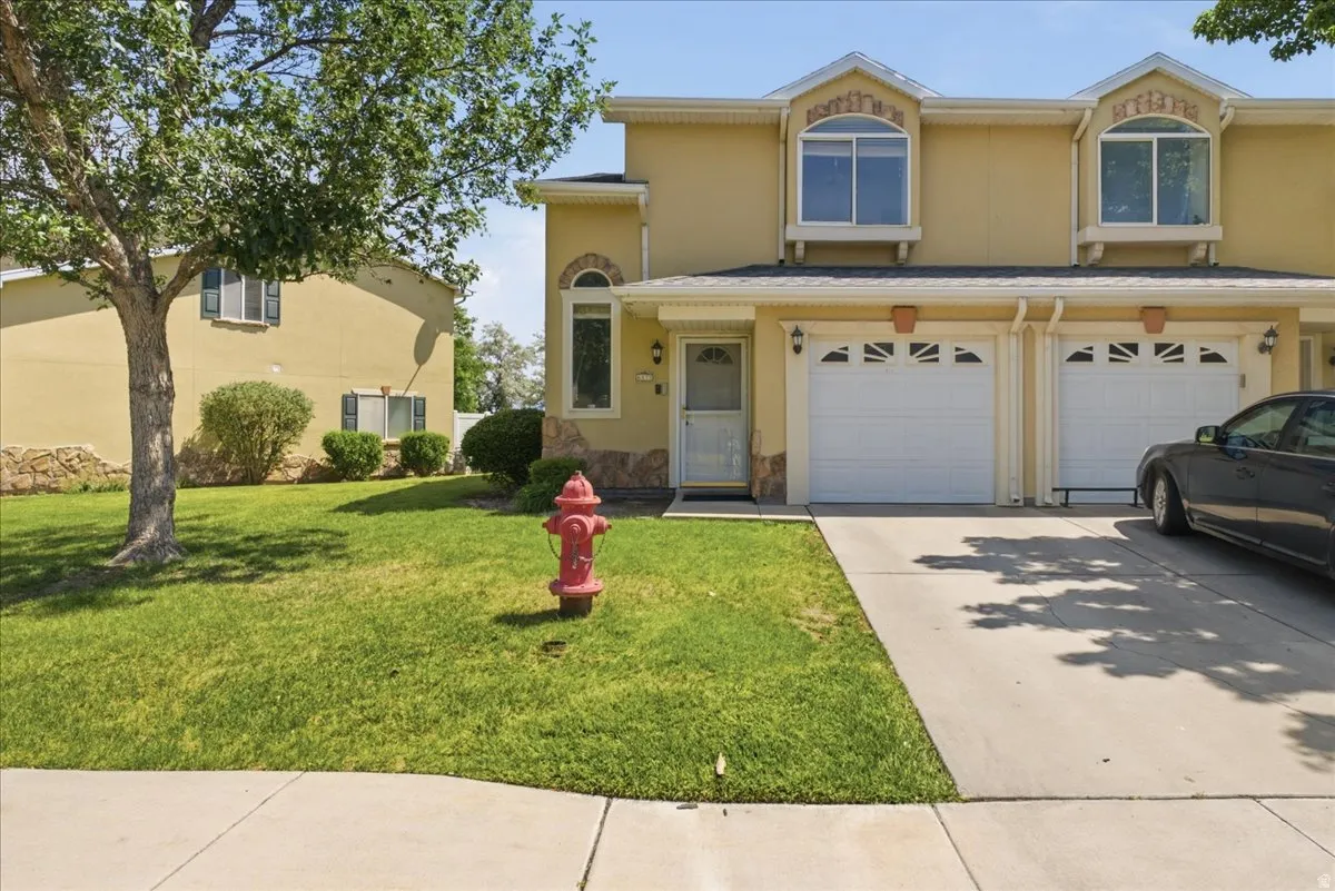 Two-story townhome with a stucco exterior, stone facade accents, and a concrete driveway