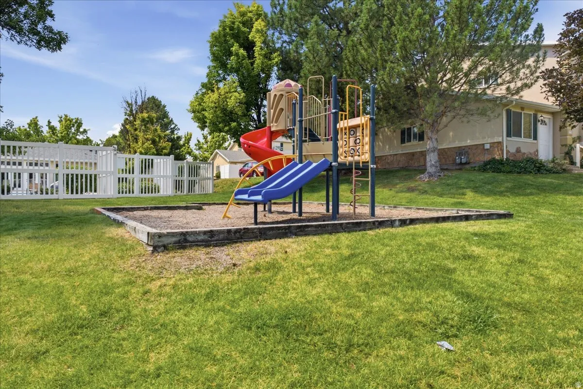 Outdoor play structure featuring multiple slides and climbing elements set within a contained sand area