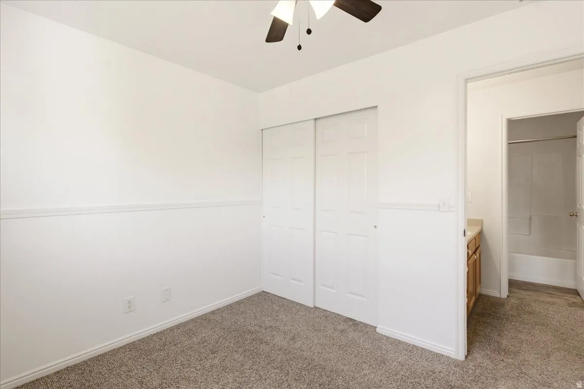 Room featuring neutral-toned carpeting, white walls, and a ceiling fan