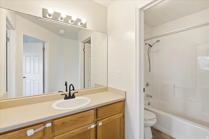 Bathroom featuring a light wood-finish vanity with a beige countertop, an oval undermount sink, and a matte black faucet