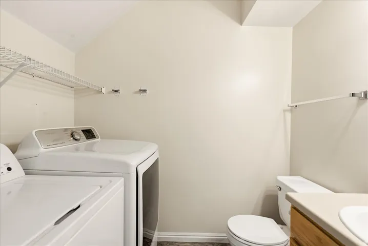 Dedicated laundry area featuring wire shelving, built-in wall hooks, and wood-finish flooring