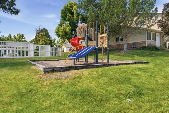 Outdoor play structure featuring multiple slides and climbing elements set within a contained sand area