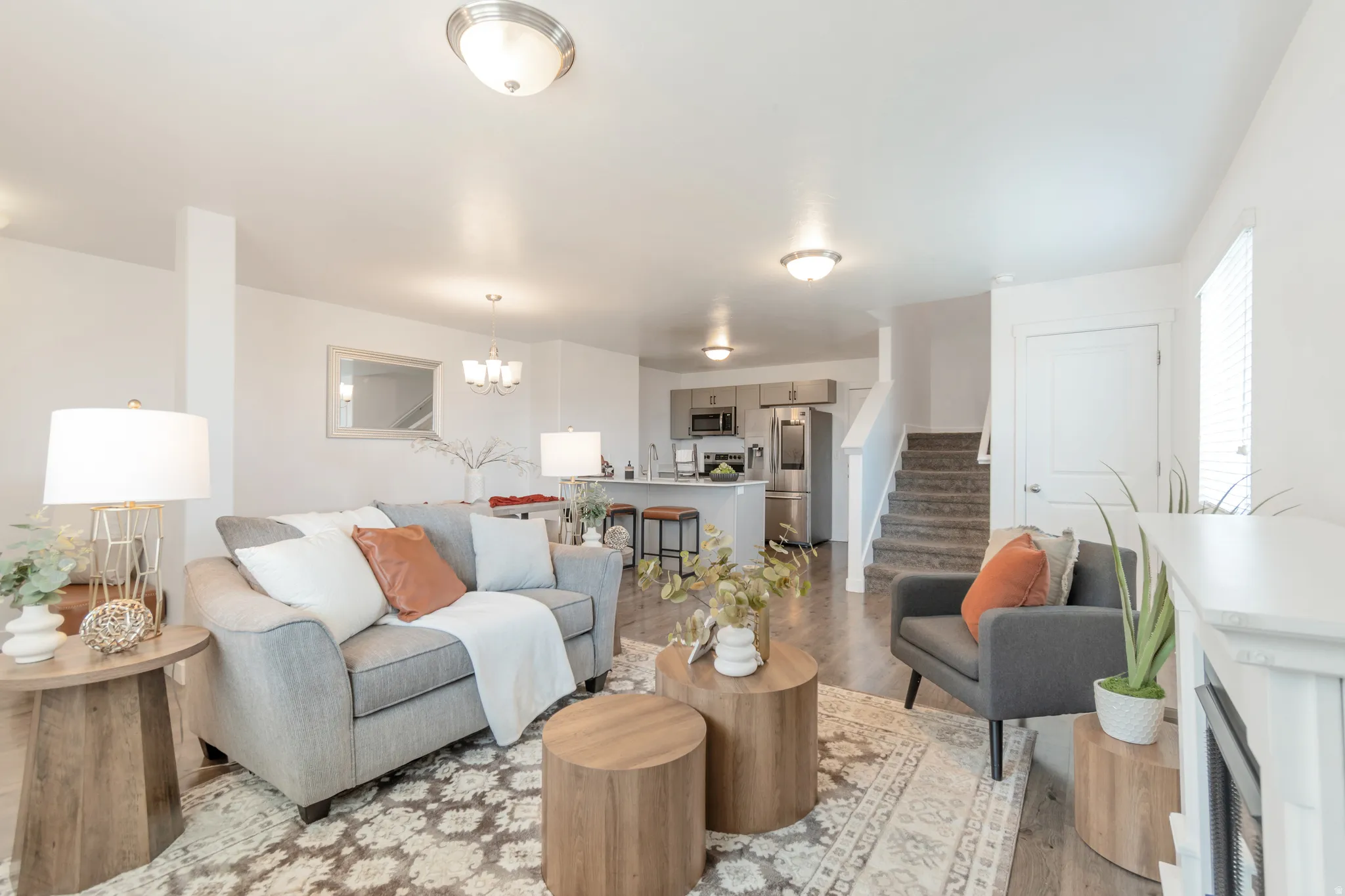 Spacious open-concept living area featuring wood-finish flooring, recessed lighting, a built-in kitchen island with seating, and a carpeted staircase