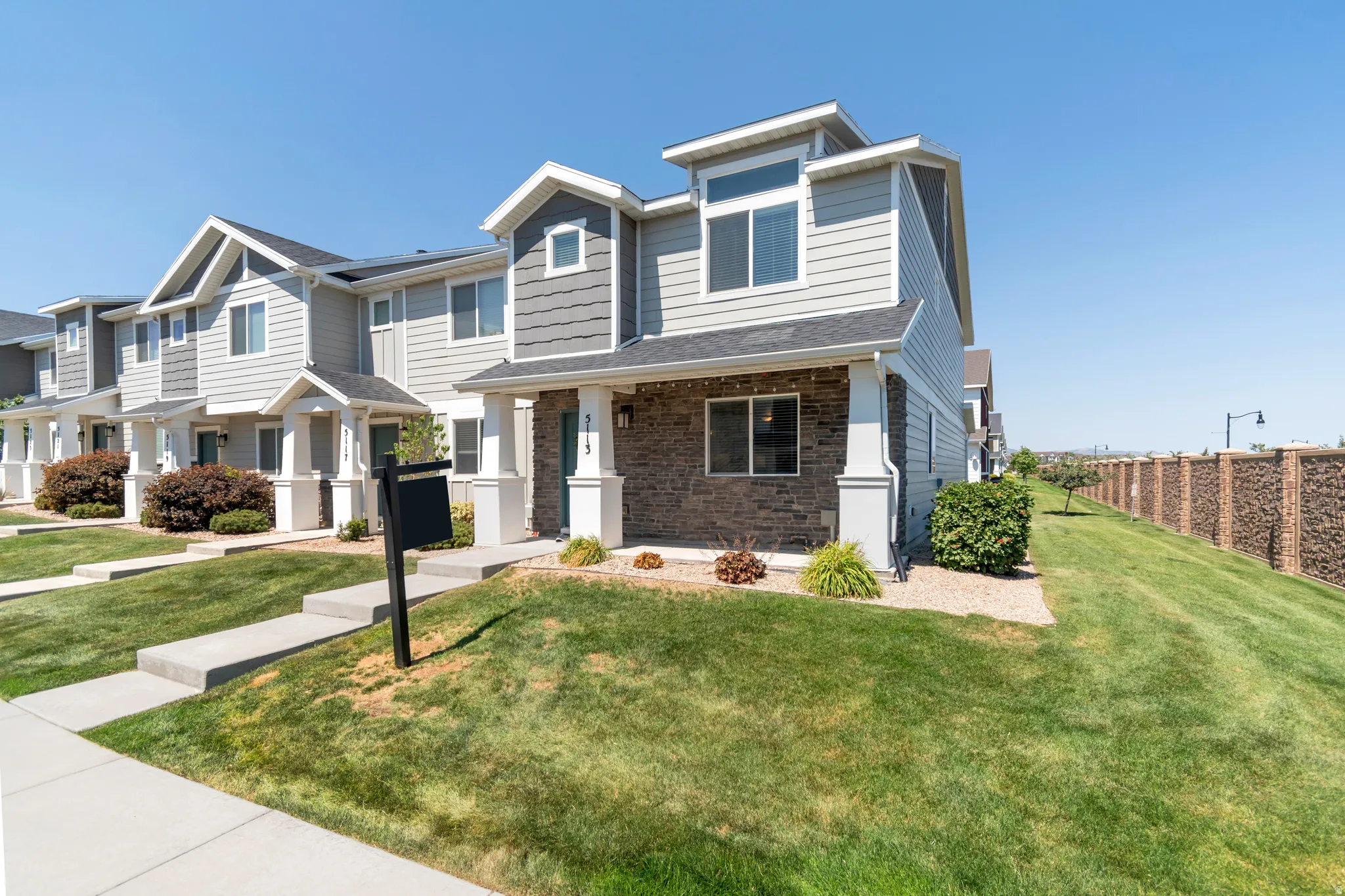 Contemporary townhome exterior featuring light gray siding, dark gray shake siding, and a stone facade