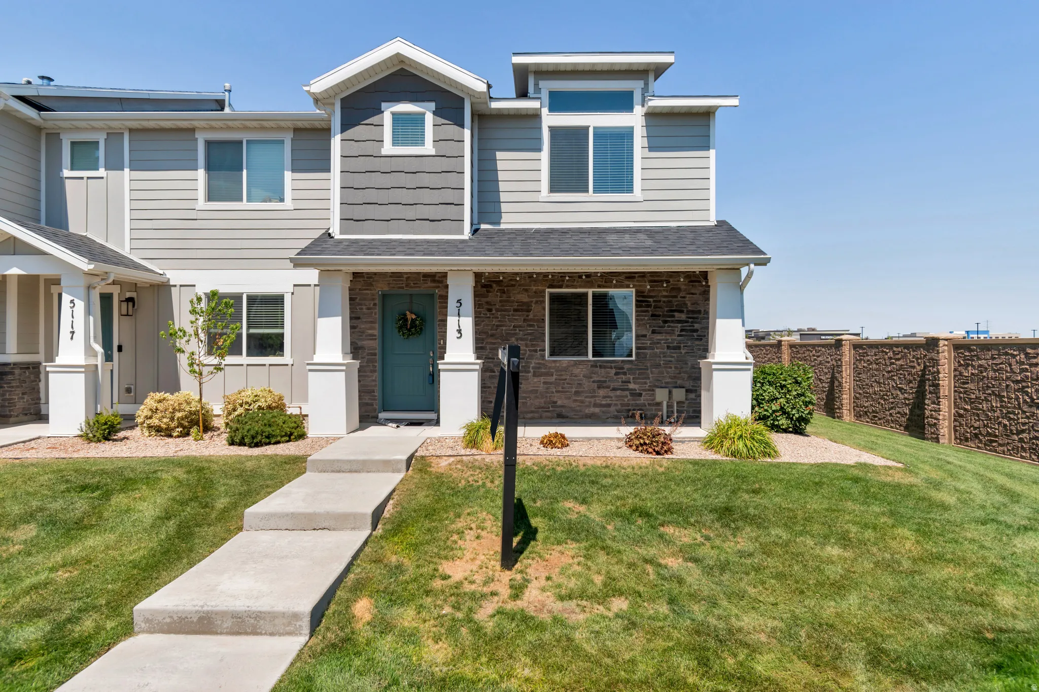 Modern townhome exterior featuring an inviting turquoise entry door, stone facade accents, and horizontal siding
