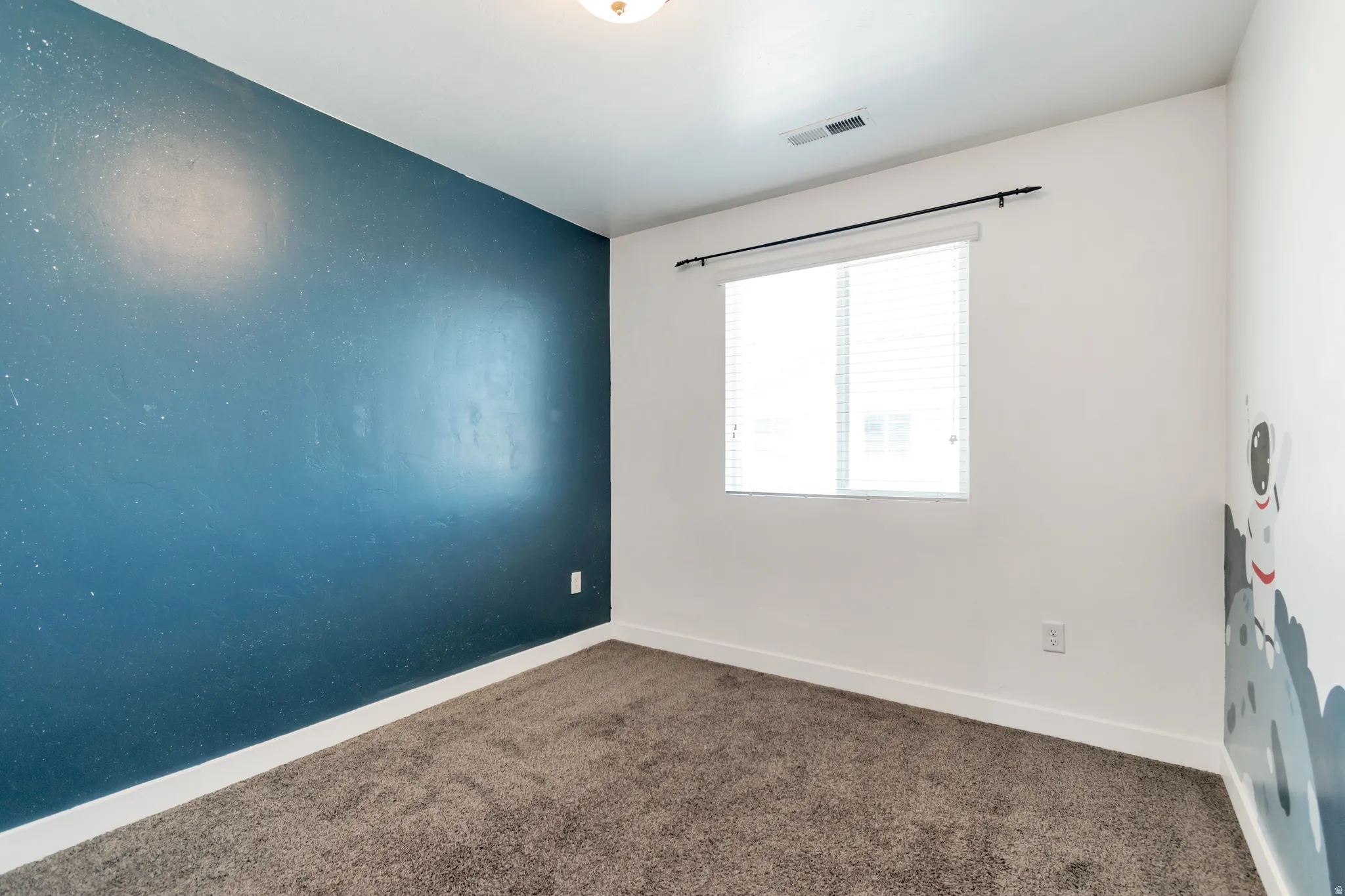 Interior room featuring a textured accent wall, white painted walls, and a single window with horizontal blinds