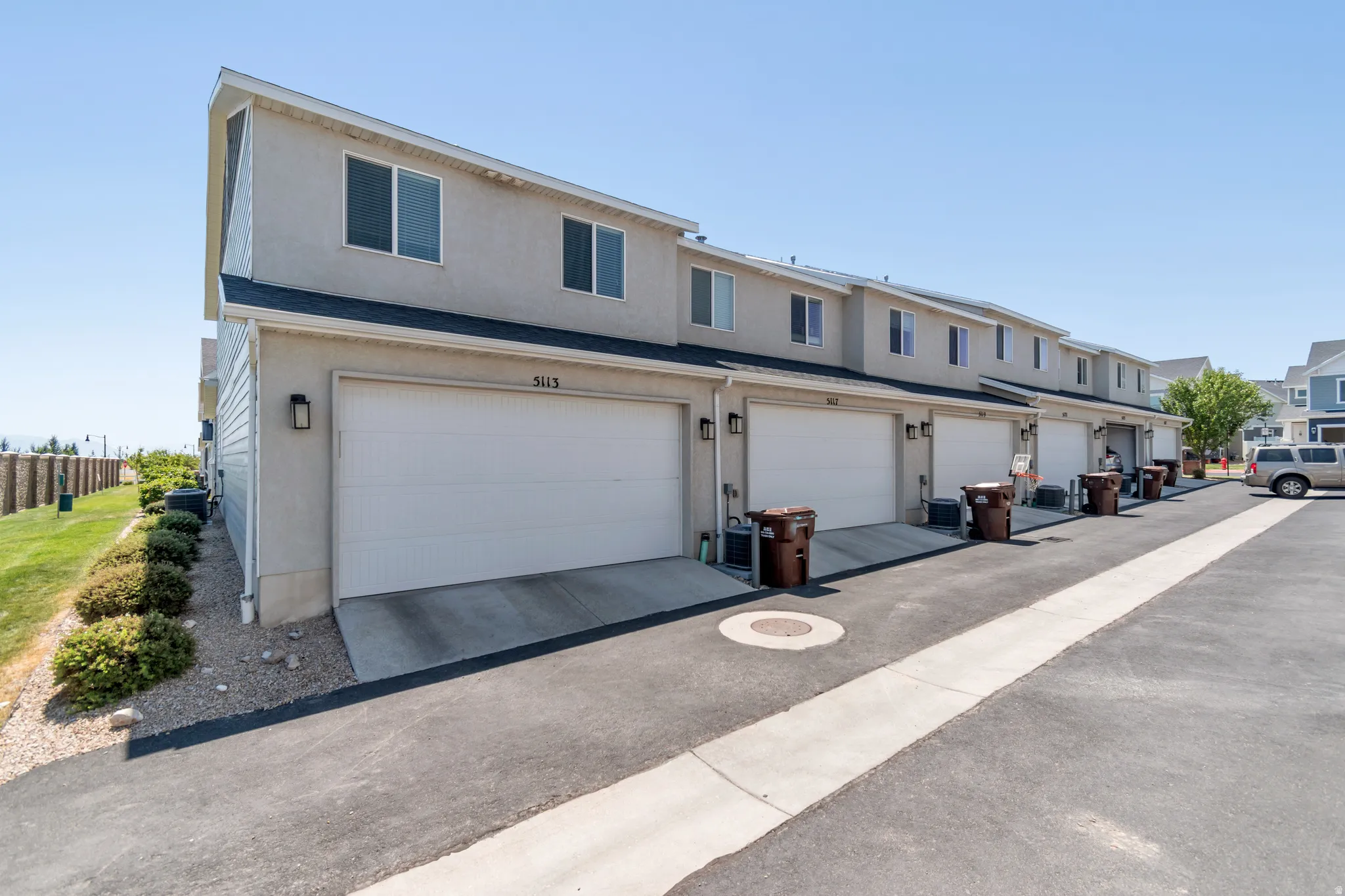 Multi-unit townhome-style residences featuring attached garages, paved driveways, and upper-level windows