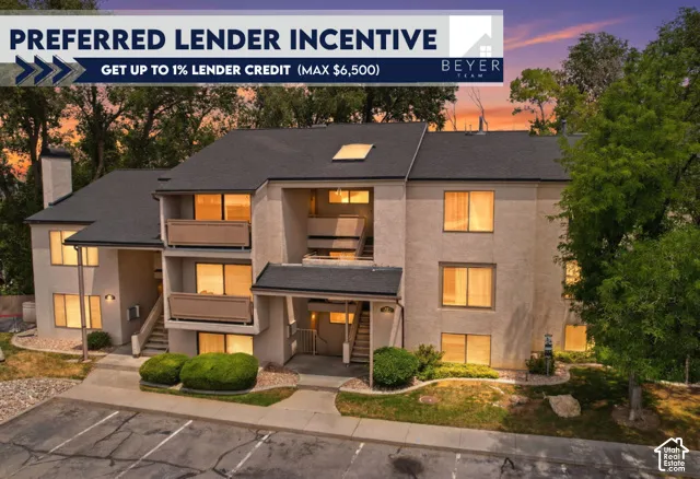 Multi-story building exterior featuring stucco siding, shingled roofing, private balconies, and integrated skylights surrounded by mature landscaping