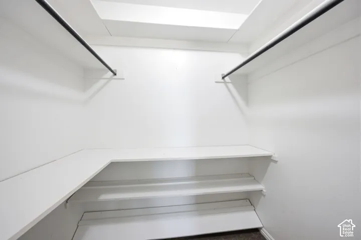 Walk-in closet featuring white walls, white shelving, and dual hanging rods
