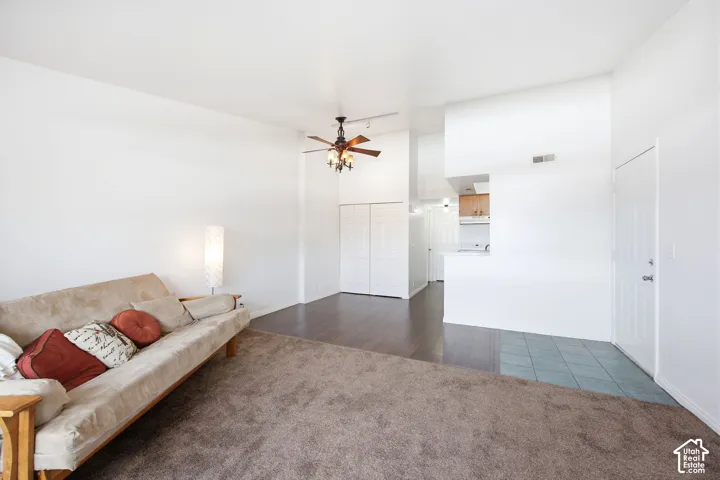 Open-concept living area featuring a ceiling fan with integrated lighting, wood-finish flooring, and a partial wall separating spaces