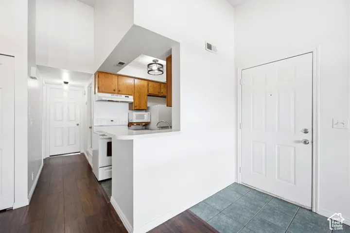 Entryway featuring a kitchen pass-through, wood-finish flooring, and vaulted ceilings