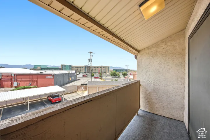 Balcony featuring a partial mountain backdrop, stucco exterior, and a protective railing