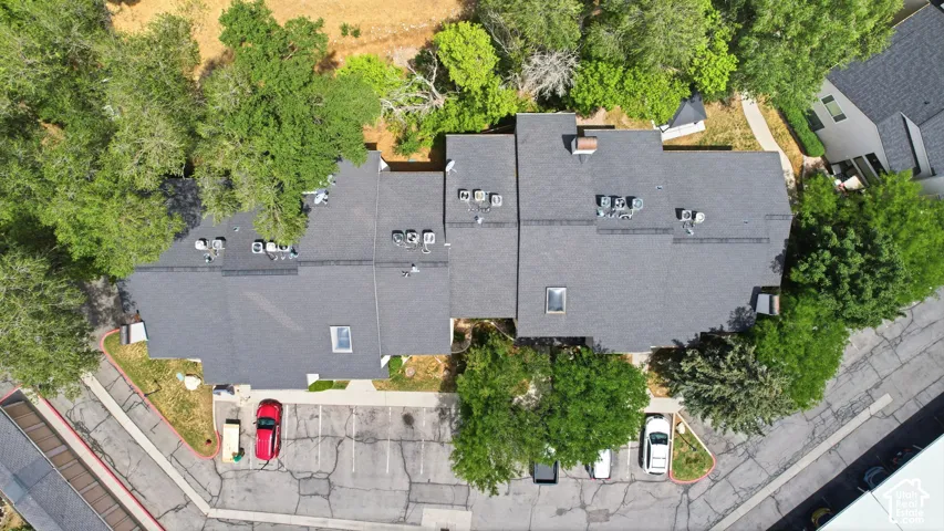 Multi-unit building featuring dark shingle roofing, multiple skylights, and individual exterior HVAC units