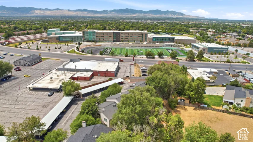 Aerial perspective showcasing a commercial building with an expansive paved parking lot and covered parking structures