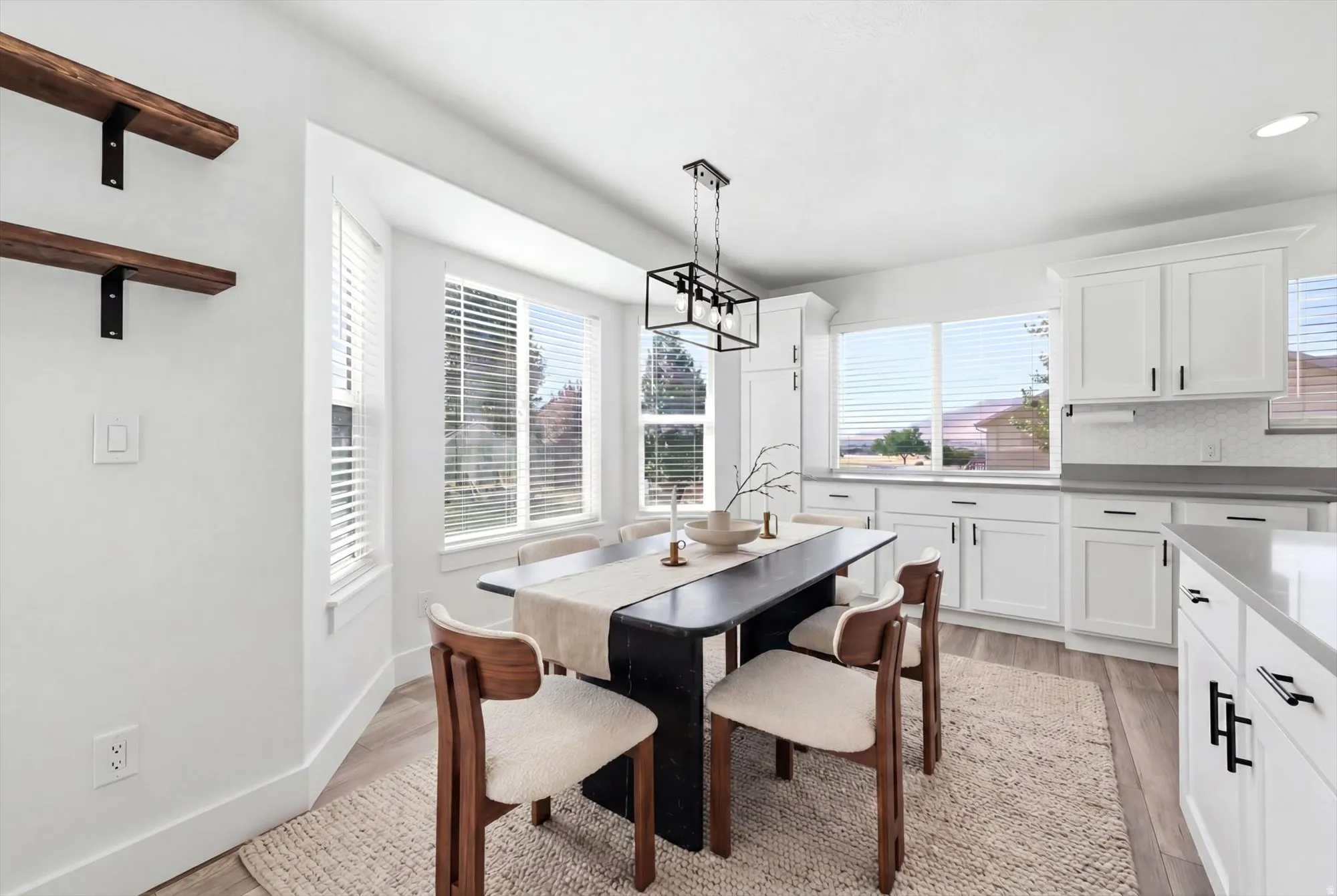 Open-concept dining area featuring a modern black chandelier and wood-finish flooring