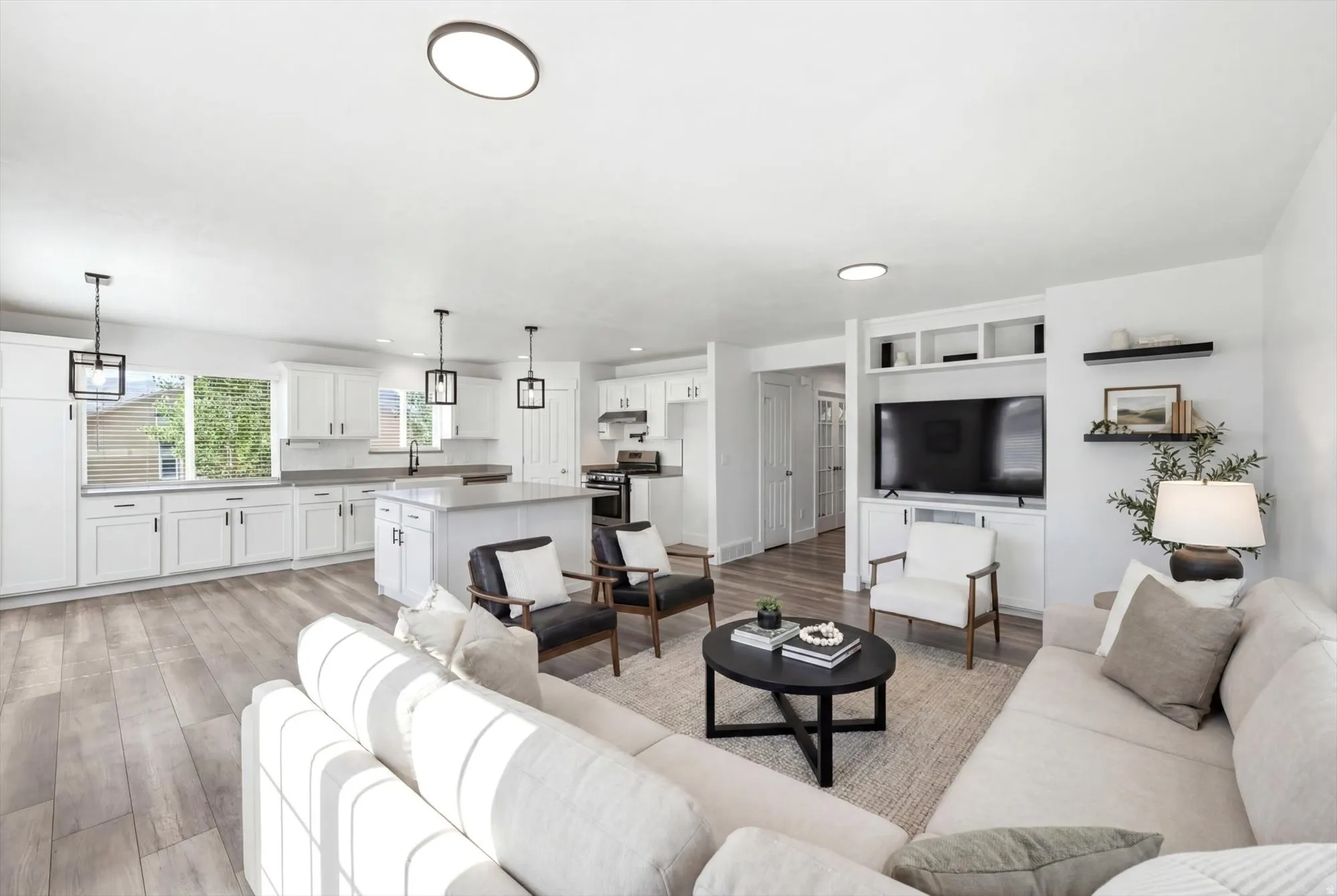 Open-concept living space featuring wood-finish flooring, recessed lighting, and a built-in media center