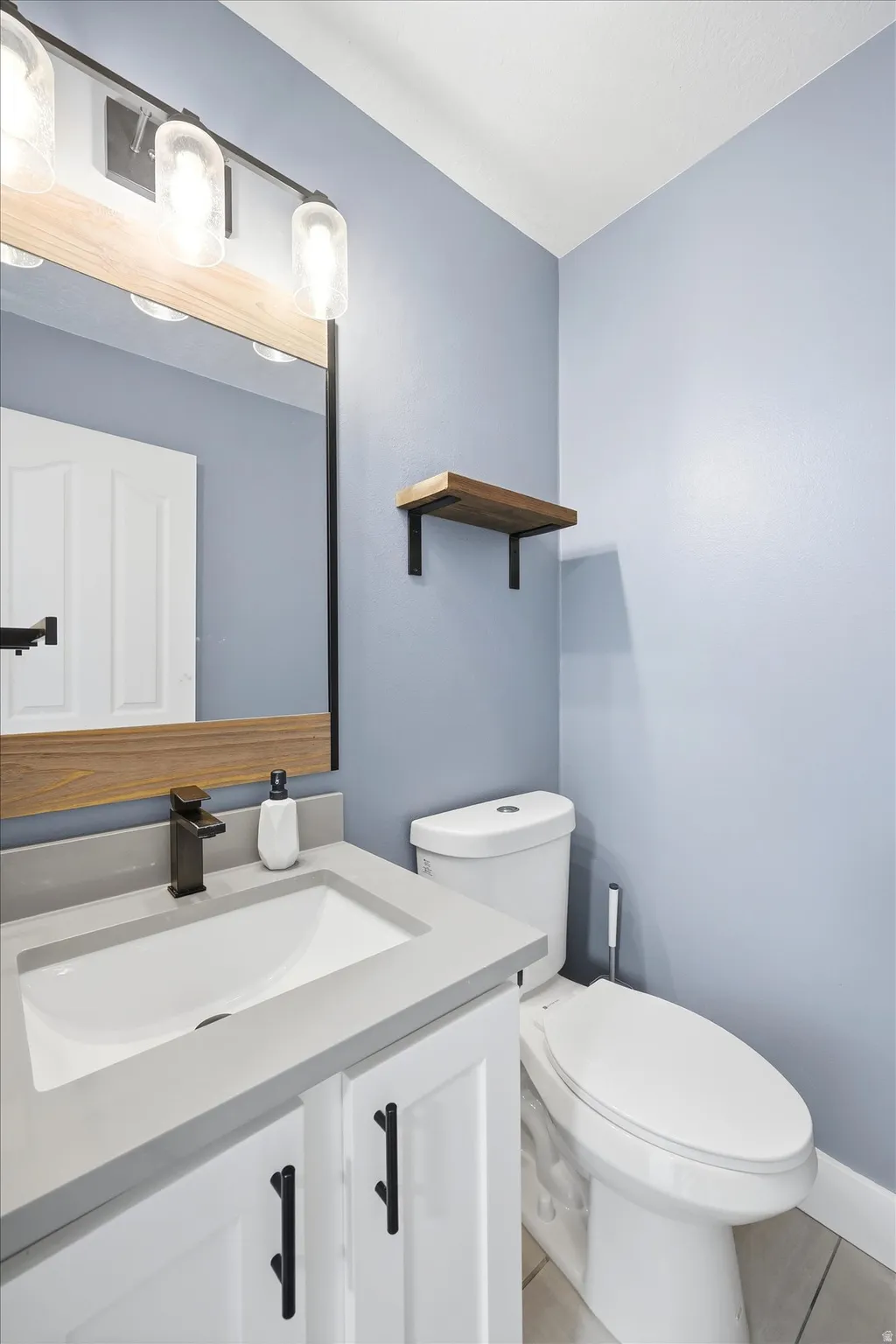 Bathroom featuring a white vanity with a gray countertop, an undermount sink, and a matte black faucet