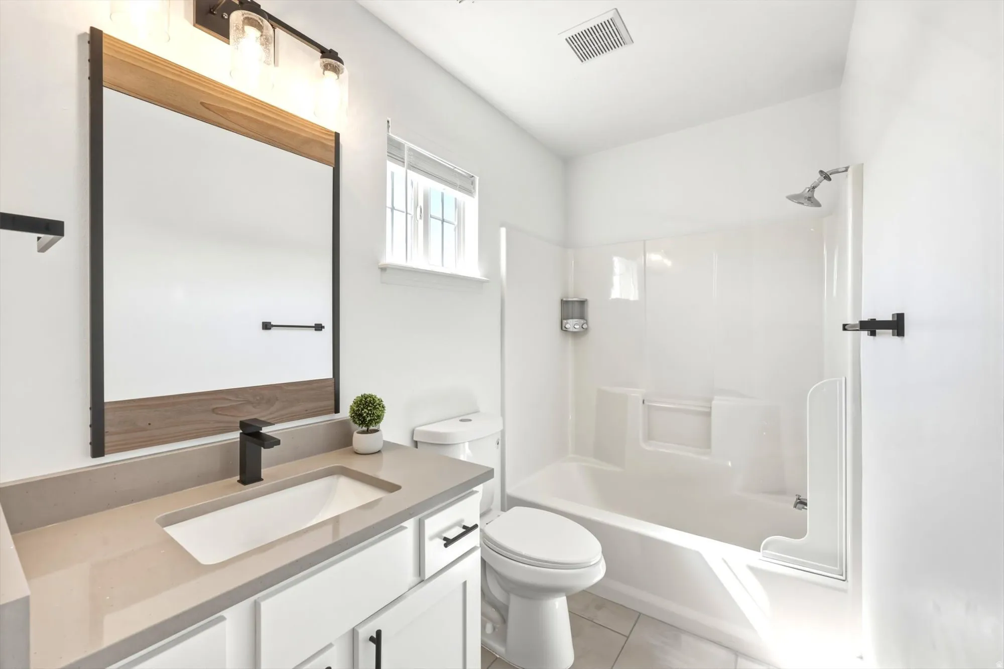 Modern bathroom featuring a quartz countertop vanity with an integrated sink and matte black faucet