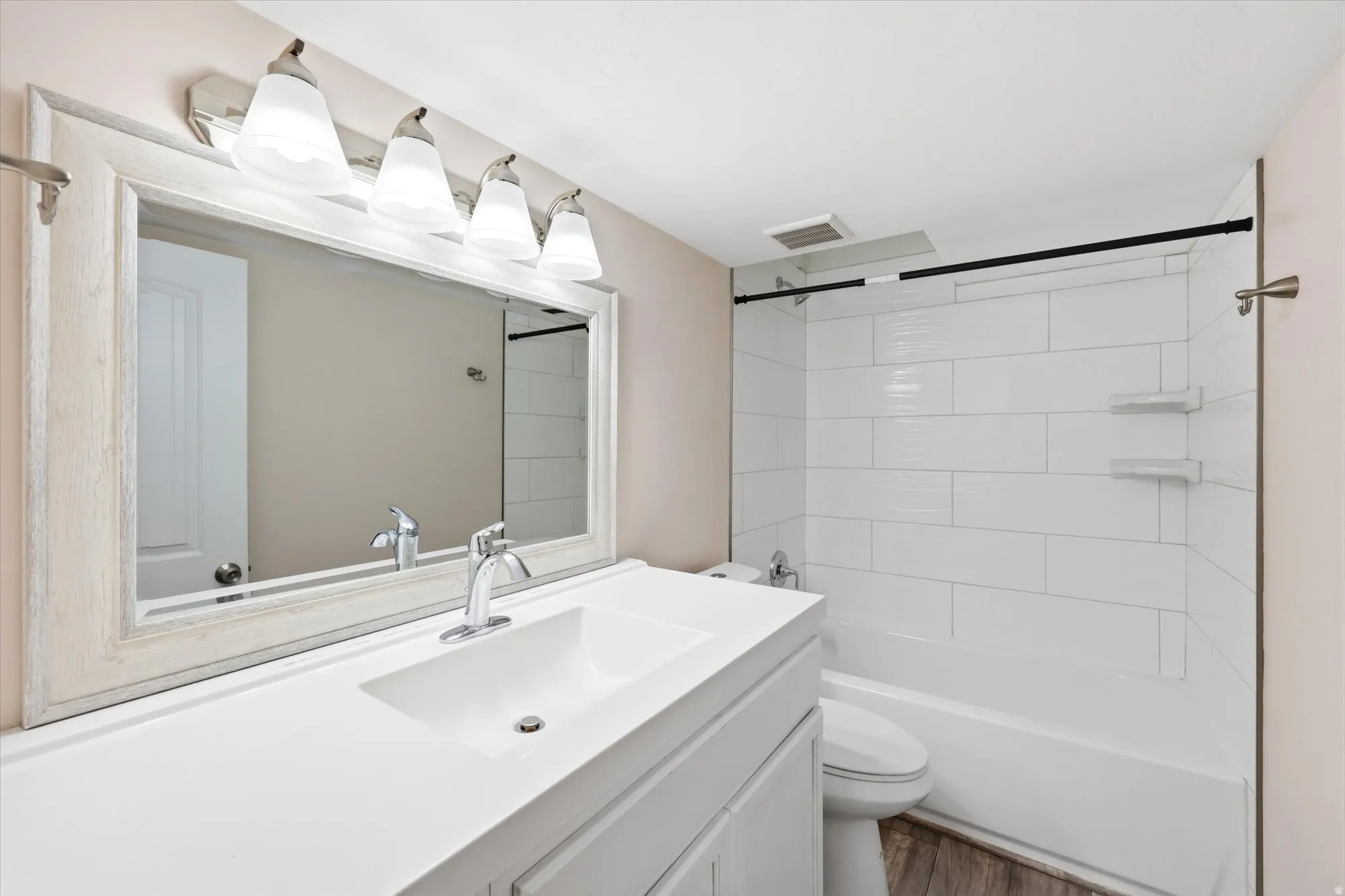 Bathroom featuring a single vanity with integrated sink, chrome faucet, and a framed mirror